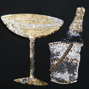 May include: A gold and silver sequined champagne glass and bottle with a silver sequined ice bucket.