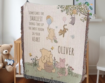 Puede incluir: Una manta tejida de temática Winnie de Pooh con una cita que dice "A veces las cosas más pequeñas ocupan el mayor espacio en tu corazón". La manta presenta a Winnie de Pooh, Piglet, Tigger y Eeyore. La manta está personalizada con el nombre "Oliver".