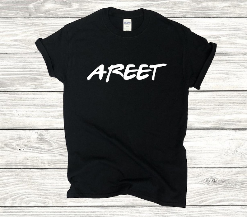 May include: Black t-shirt with the white word "AREET" in a handwritten style. The shirt is made of a soft material and has a classic crew neck. The image is taken on a light wood grain background.