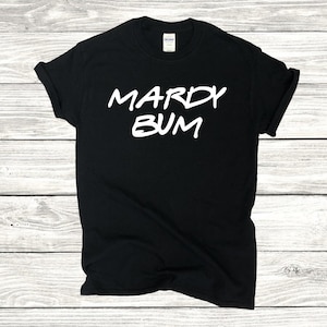 May include: Black t-shirt with white text that reads "Mardy Bum".