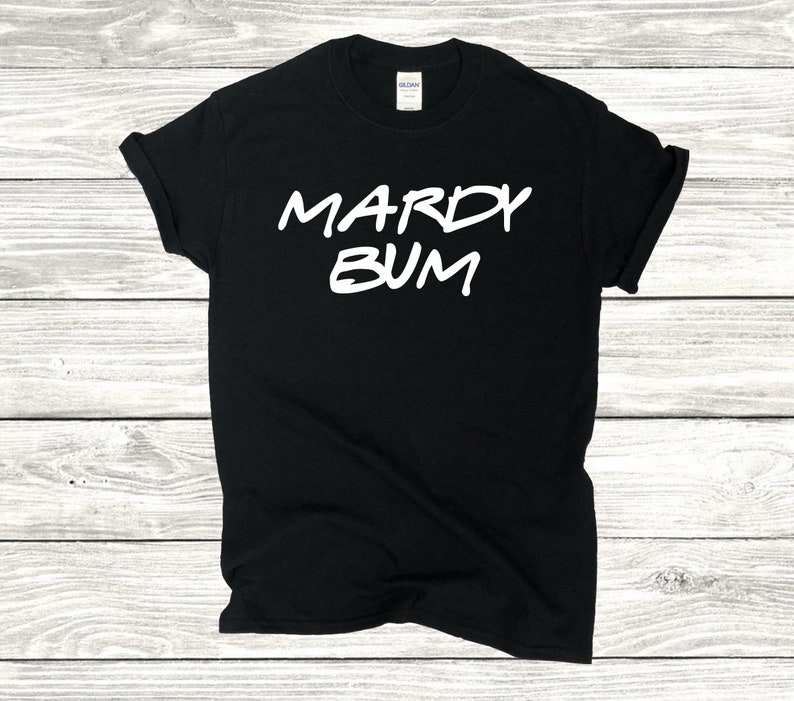 May include: Black t-shirt with white text that reads "Mardy Bum".