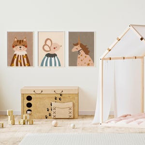 May include: Three framed art prints featuring whimsical animal illustrations: a cat, a mouse, and a unicorn. The cat wears a striped cape, the mouse a striped shirt, and the unicorn is adorned with stars. A wooden toy chest and play tent are also visible.