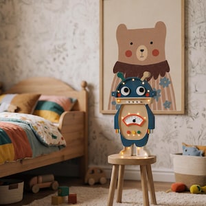 May include: A wooden robot-shaped night light with a blue head and body, standing on a small wooden stool. The night light has a gauge and lights. A framed bear illustration hangs on the wall behind it. A wooden bed and toys are in the background.