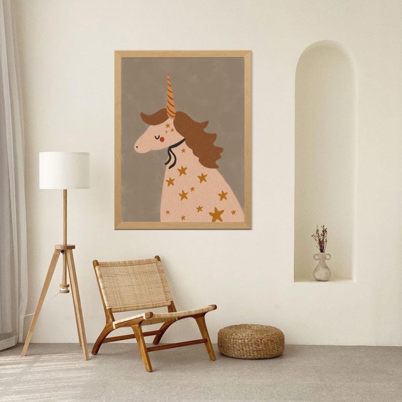 May include: A framed print featuring a whimsical unicorn illustration. The unicorn has a pink body adorned with gold stars, a brown mane, and a golden horn. The artwork is set against a muted gray background, framed in natural wood.