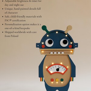 May include: A wooden robot-shaped night light with a blue head and body, beige torso, and white feet. It features a gauge-like design on its chest and emits a warm glow. The robot has two antennae and is hand-painted.