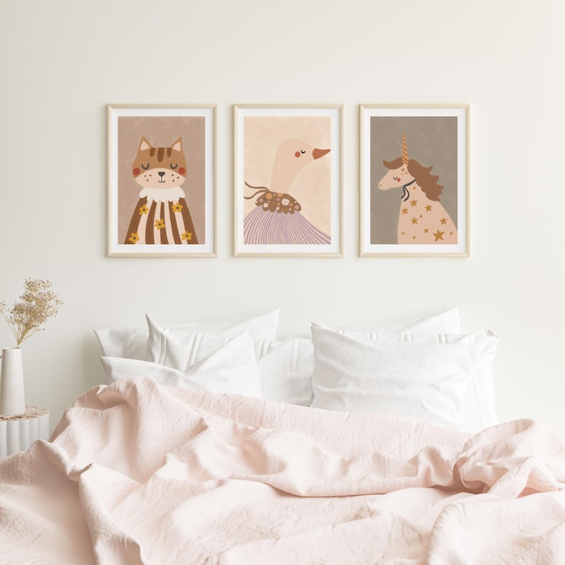 May include: Three framed art prints featuring whimsical animal illustrations. The prints depict a cat, a goose, and a unicorn, each with unique decorative elements. The color palette includes soft browns, pinks, and creams, creating a gentle and inviting aesthetic.