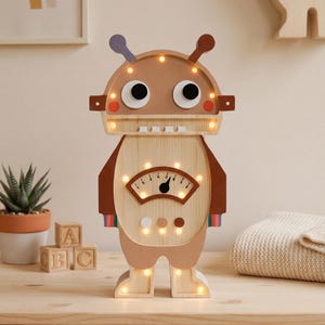 May include: Wooden robot-shaped night light with a light brown head and body, featuring a gauge and glowing lights. The robot has large black eyes, brown accents, and colorful stripes on the arms. The light is designed for a child's room.
