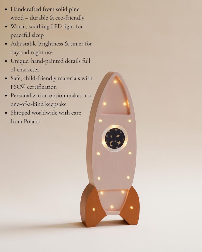 Op de afbeelding: Een roze houten raket nachtlampje met warme LED-verlichting. De raket heeft bruine vinnen en een rond raam met een sterrenhemel ontwerp. De tekst zegt "Handcrafted from solid pine wood - durable & eco-friendly".