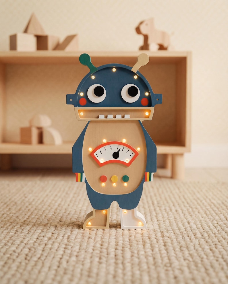 May include: A wooden robot-shaped night light with a navy blue head, tan body, and light-up features. The robot has large eyes, antennae, and a gauge on its chest. The light has a retro design and is suitable for a child's room.