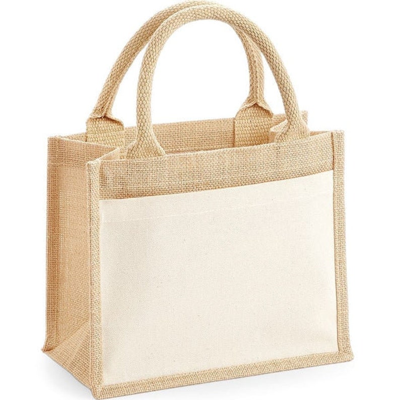 Puede incluir: Una peque&ntilde;a bolsa de mano de yute de color natural con un panel de lona blanca. La bolsa tiene dos asas resistentes y es perfecta para llevar objetos peque&ntilde;os.