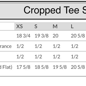 May include: Cropped tee sizing chart with measurements in inches for XS, S, M, L, XL, and 2XL sizes. Measurements include body length, body length tolerance, chest tolerance, and chest width laid flat.