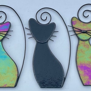 May include: Five stained glass cat figurines. Two are iridescent blue and green, two are iridescent pink and green, and one is black.