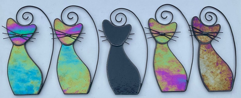 May include: Five stained glass cat figurines. Two are iridescent blue and green, two are iridescent pink and green, and one is black.
