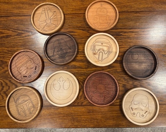 May include: A collection of wooden coasters with various Star Wars character designs, including Darth Vader, a Stormtrooper, and the Millennium Falcon. The coasters are round and made of different wood tones.