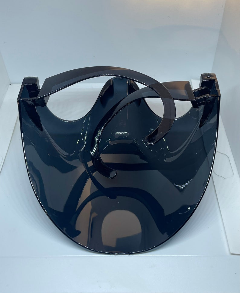 Op de afbeelding: Een zwart plastic gezichtsschild met een gebogen vizier en een verstelbaar hoofdband. Het schild is ontworpen om het gezicht van de drager te beschermen tegen spatten en druppels.