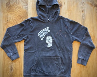 Upcycled hoodie enhanced with kitschy graphics and embroidered hearts. Price includes donation to charity.