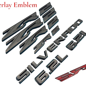May include: A collection of dark gray overlay emblems, including the text "Overlay Emblem", "Silverado", "6.2L", and "SS". The emblems are designed for automotive use and are displayed against a white background.