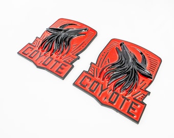May include: Two red and black metal emblems with a coyote head design and the word "COYOTE" in black lettering.