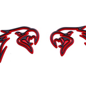 May include: Two black and red stylized eagle head designs. The eagle heads are facing opposite directions. The eagle heads are outlined in red and filled in black.