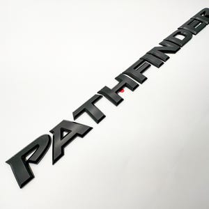May include: Black plastic "PATHFINDER" lettering for a vehicle.