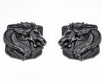 May include: A pair of black metal emblems featuring a horse and snake design. The emblems are detailed and have a textured surface.