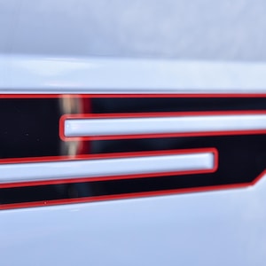 May include: A close-up of a white surface with a black and red number "5" on it. The number is outlined in red and has a black fill.