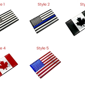 May include: Rectangular flag-themed accessories. Style 1 features a black and white American flag. Style 2 has a blue stripe. Style 3 displays a Canadian flag. Style 4 shows a red and white Canadian flag. Style 5 is a red, white, and blue American flag.