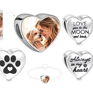May include: Silver heart-shaped charms featuring a photo of a woman and a dog, a paw print, and the phrases "Love you to the MOON and back" and "Always in my heart." A bracelet with a photo charm is also shown.