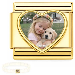 May include: A gold-coloured charm with a heart-shaped frame. The frame features a photo of a young girl with a puppy, and the words "Custom image here". A white bracelet with a small charm is in the lower left corner.