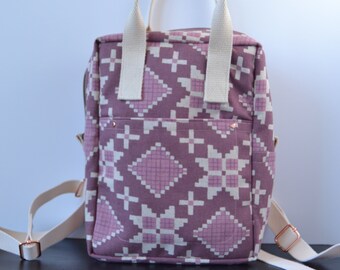 May include: A purple and white patterned backpack with white straps and copper accents. The backpack has a geometric design with a diamond pattern.