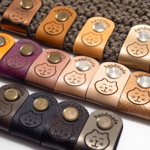 Etiquetas plegables personalizadas con remaches (juego de 25) de piel sintética para prendas de punto y crochet.
