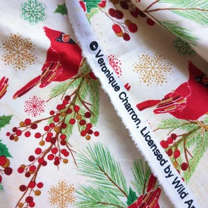 Tela de algodón de 44" x 70" con pájaros cardenales rojos sobre fondo beige, estampado navideño de invierno, acebo verde, pino y copos de nieve. imagen 5