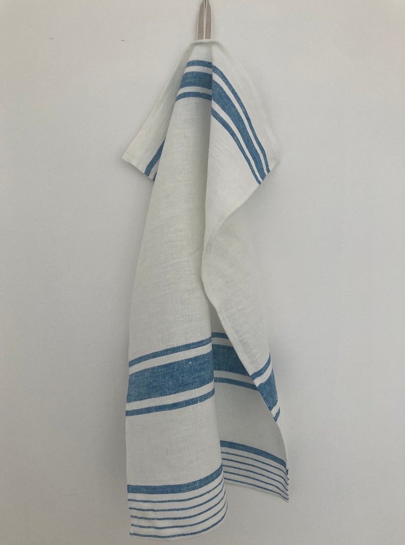 May include: White kitchen towel with blue stripes hanging on a hook.