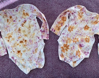 May include: Two white long-sleeved shirts with a tie-dye pattern in shades of orange, pink, and white. The shirts have a floral design.
