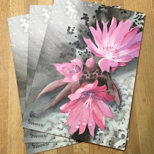 May include: A set of three watercolor prints featuring pink flowers with a gray and black background.