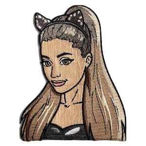 May include: Embroidered patch featuring a stylized portrait of a woman with long, light brown hair in a high ponytail. She wears a black top and a headband with cat ears. The patch has a tan background and is outlined in black.