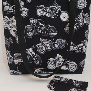 May include: Black tote bag with a white motorcycle print. The bag has two black straps and a matching black zippered pouch.