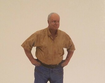 May include: A figurine of a man wearing a brown short-sleeved shirt and blue jeans. He is standing with his hands on his hips.