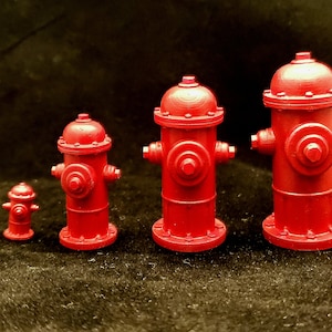 May include: Four red fire hydrants of different sizes, the smallest is about 2 inches tall, the largest is about 6 inches tall.