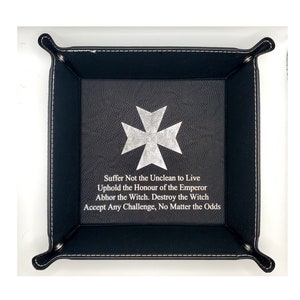 May include: Black leather dice tray with a white cross and the text "Suffer Not the Unclean to Live Uphold the Honour of the Emperor Abhor the Witch. Destroy the Witch Accept Any Challenge, No Matter the Odds".