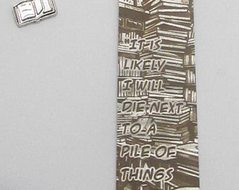 May include: A silver bookmark with a chain and a book charm. The bookmark features a stack of books with the text "It is likely I will die next to a pile of things I was meaning to read." and "Lemony Snicket" at the bottom.