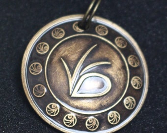 May include: A bronze pendant with a stylized letter V design and a circle of smaller decorative circles around the edge.