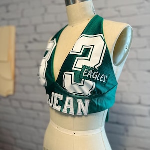 May include: Green and white halter top with the number 2 and the word "EAGLES" on it. The top is made from a jersey material.