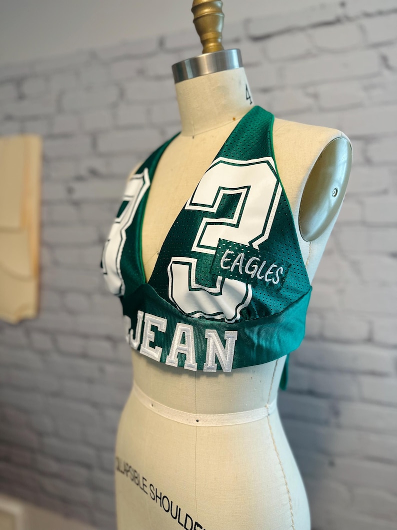 May include: Green and white halter top with the number 2 and the word "EAGLES" on it. The top is made from a jersey material.