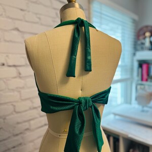 May include: A green halter top with a mesh fabric and a bow tie in the back.
