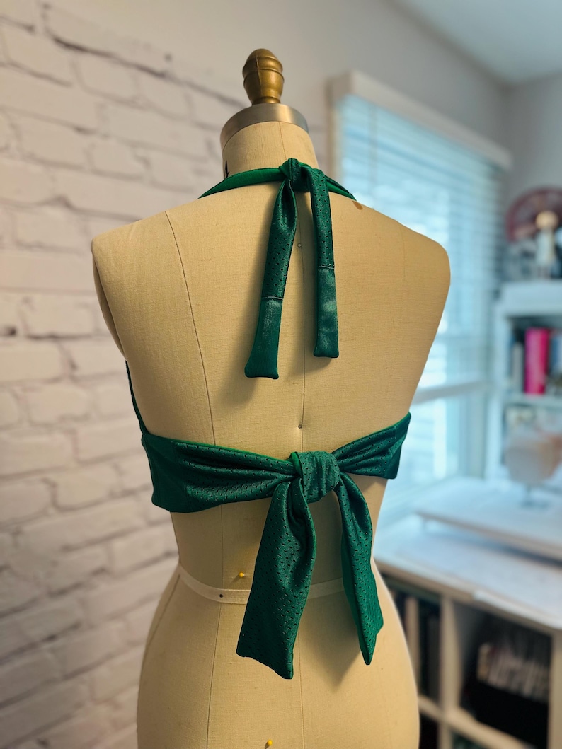 May include: A green halter top with a mesh fabric and a bow tie in the back.