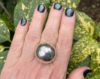 Op de afbeelding: Een zilveren ring met een grote, ronde, gladde en glanzende bolvormige steen.