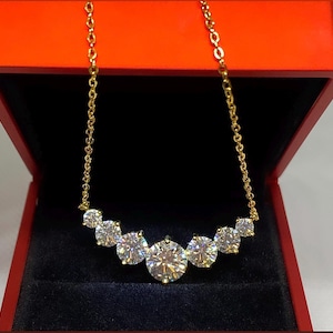 May include: A gold chain necklace with a row of six round, clear, sparkling stones. The necklace is in a red velvet box.