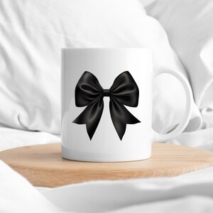 May include: White ceramic mug featuring a black satin bow design.
