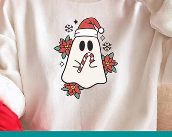 May include: White sweatshirt featuring a cartoon ghost wearing a Santa hat and holding a candy cane. The ghost is surrounded by red poinsettias and snowflakes. The bottom of the image displays the text "SVG / PNG / DXF / PDF".